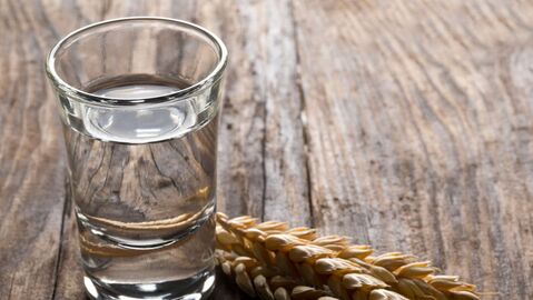 Ein Glas Wasser steht neben Getreide auf einem Holztisch