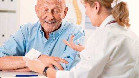 Ärztin erklärt älterem Herrn etwas zu einem Medikament