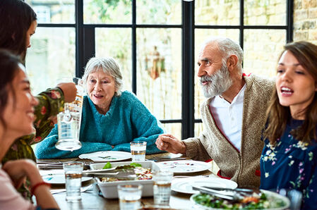 Fünf Personen unterhalten sich an einem gedeckten Tisch beim Essen