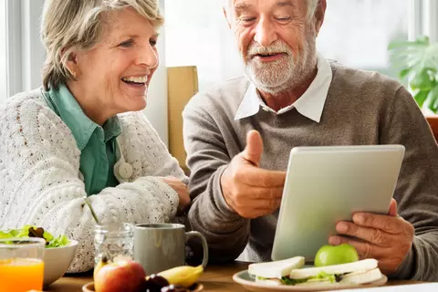 Mann zeigt seiner Frau etwas auf dem Tablet