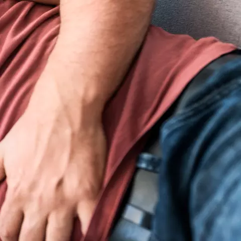 Mann liegt auf der Couch und hält sich seinen schmerzenden Bauch aufgrund Bauchkrämpfe