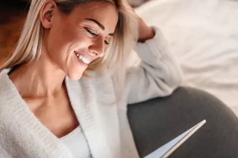 Eine lächelnde Frau schaut sich etwas auf einem Tablet an