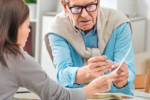 Mann und Frau schauen sich etwas auf einem Blatt Papier an