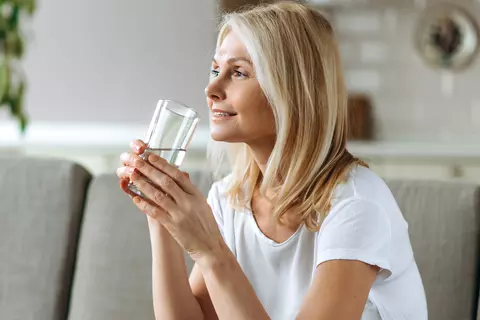 Frau trinkt ein stilles Glas Wasser