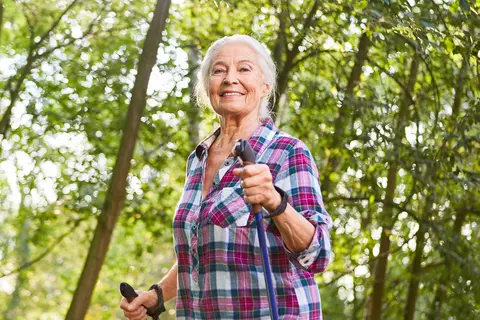 Frau mit Walking-Stöcken läuft im Wald