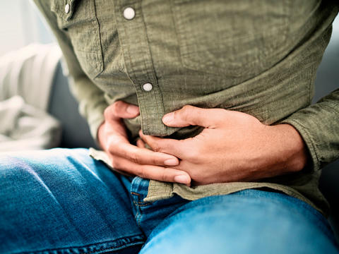 Mann hält sich den Bauch wegen Verdauungsbeschwerden