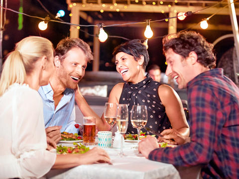 Zwei Paare sitzen lachend zusammen in einem Biergarten