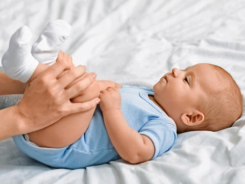Baby liegt auf ienem Bett und schaut seine Mutter an