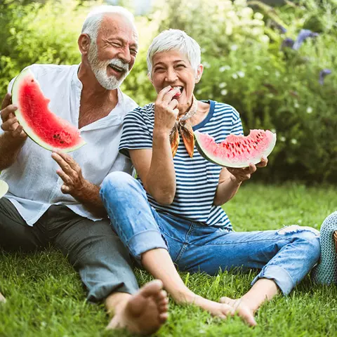 Frau und Mann essen Beschwerdefrei eine Wassermelone